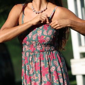 woman with brown hair wearing a teal mini dress with removable straps and smocked bodice with shell and pua print