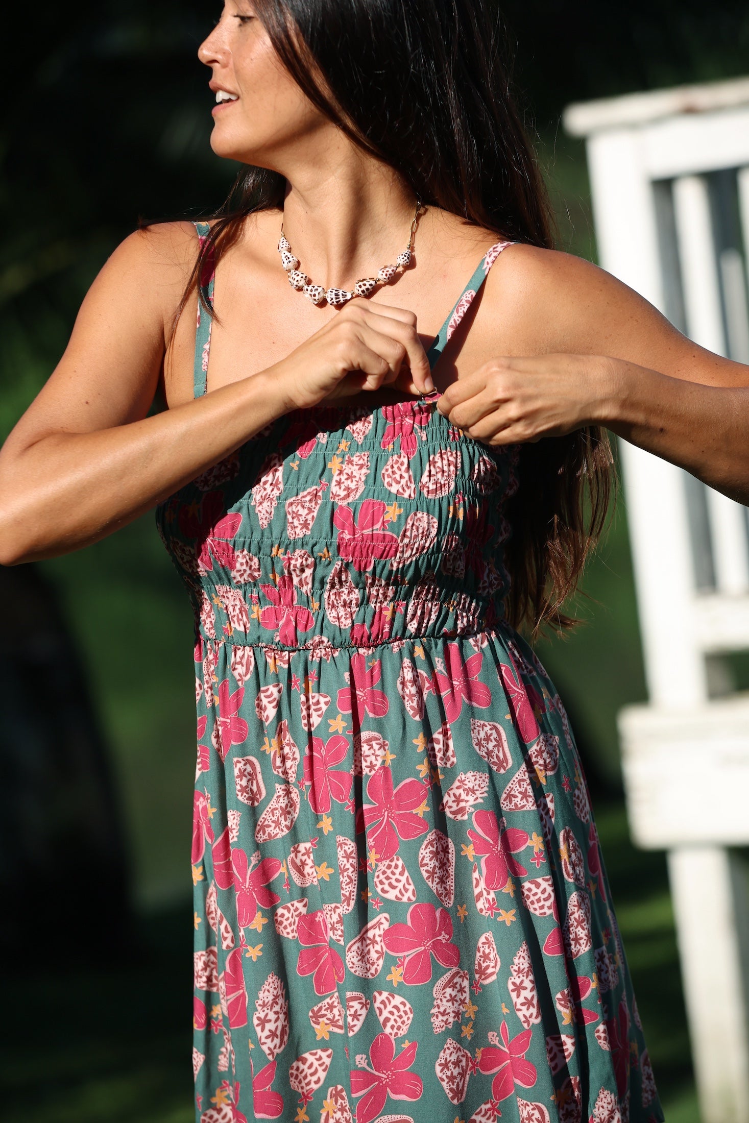 woman with brown hair wearing a teal mini dress with removable straps and smocked bodice with shell and pua print
