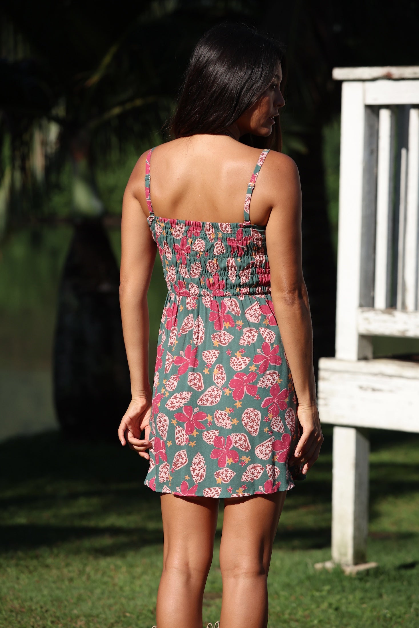 woman with brown hair wearing a teal mini dress with removable straps and smocked bodice with shell and pua print