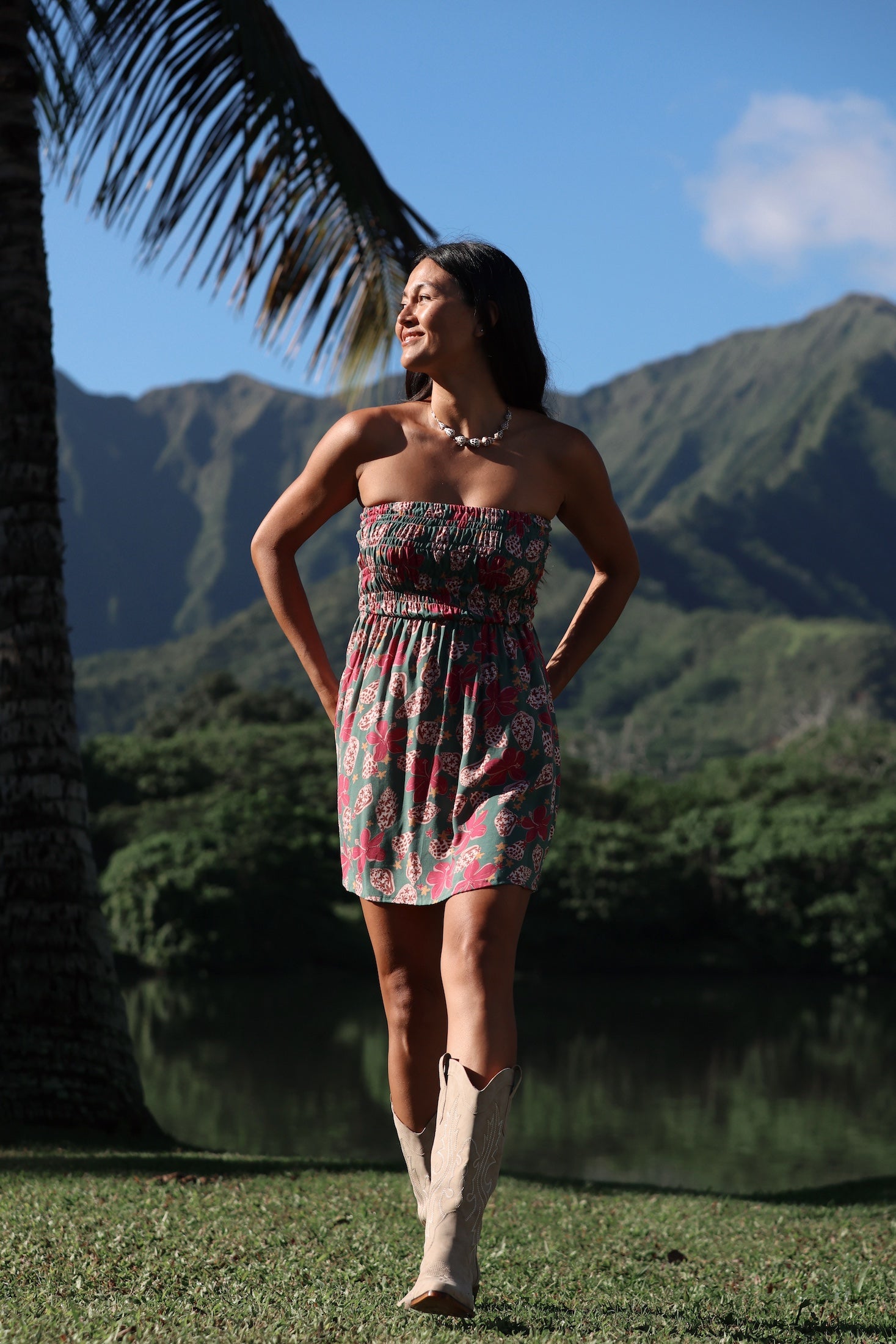 woman with brown hair wearing a teal mini dress with removable straps and smocked bodice with shell and pua print