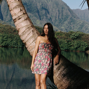 woman with brown hair wearing a teal mini dress with removable straps and smocked bodice with shell and pua print