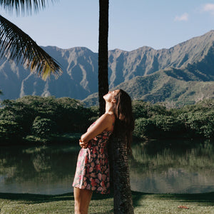 woman with brown hair wearing a teal mini dress with removable straps and smocked bodice with shell and pua print