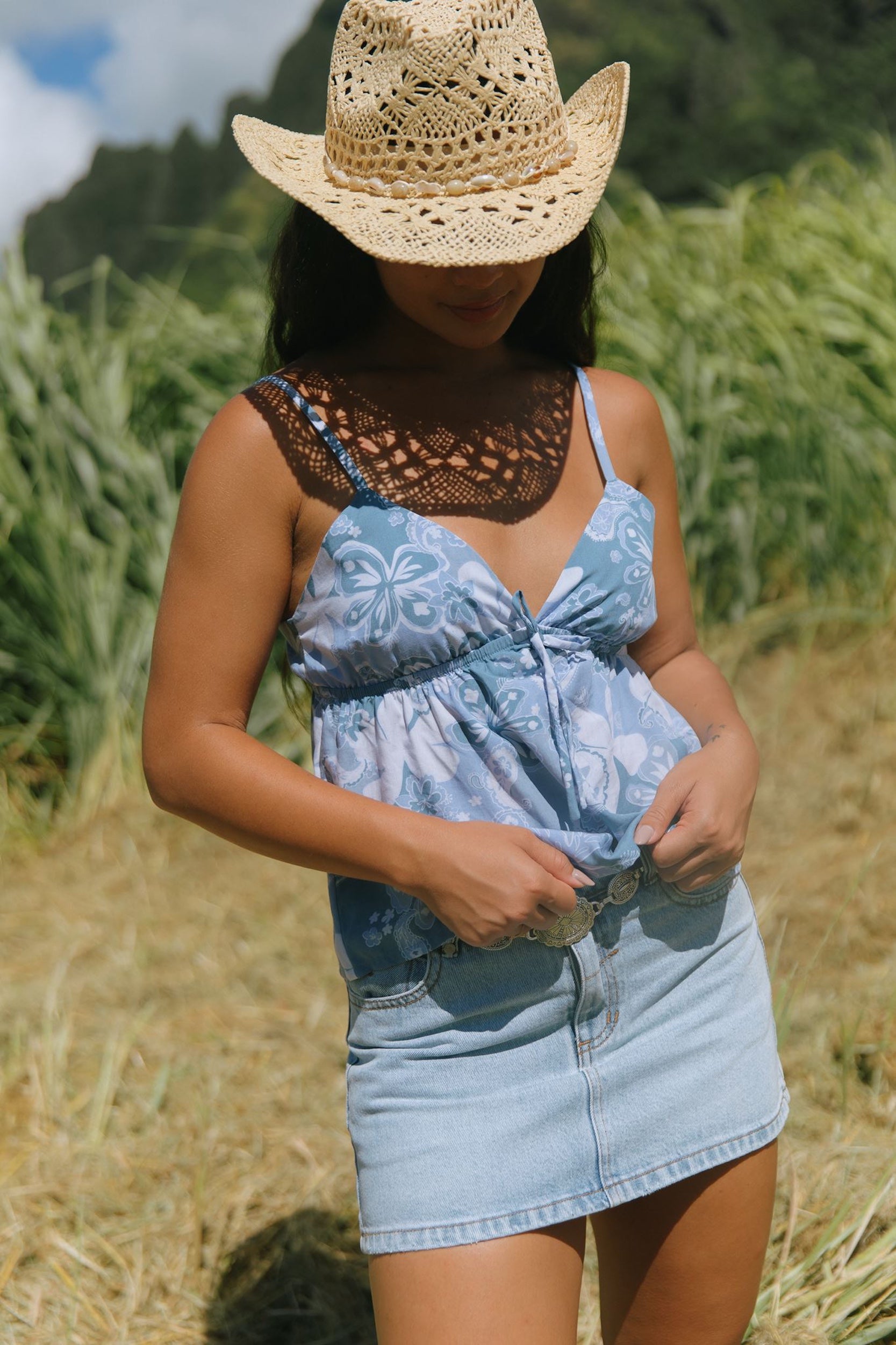 woman with brown hair wearing blue paisley printed spaghetti strap blouse with bow detail