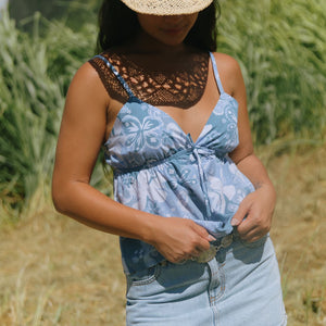 woman with brown hair wearing blue paisley printed spaghetti strap blouse with bow detail