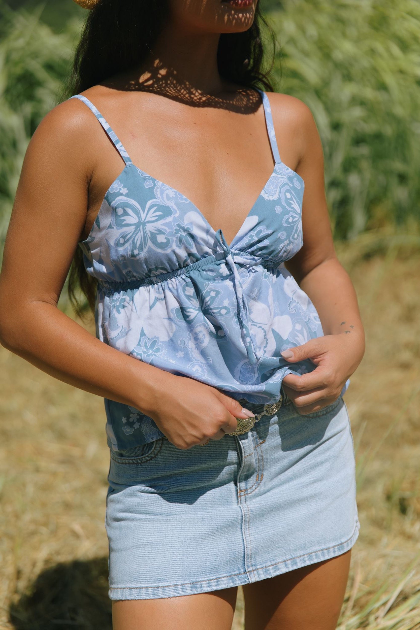 woman with brown hair wearing blue paisley printed spaghetti strap blouse with bow detail