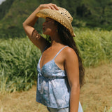 woman with brown hair wearing blue paisley printed spaghetti strap blouse with bow detail