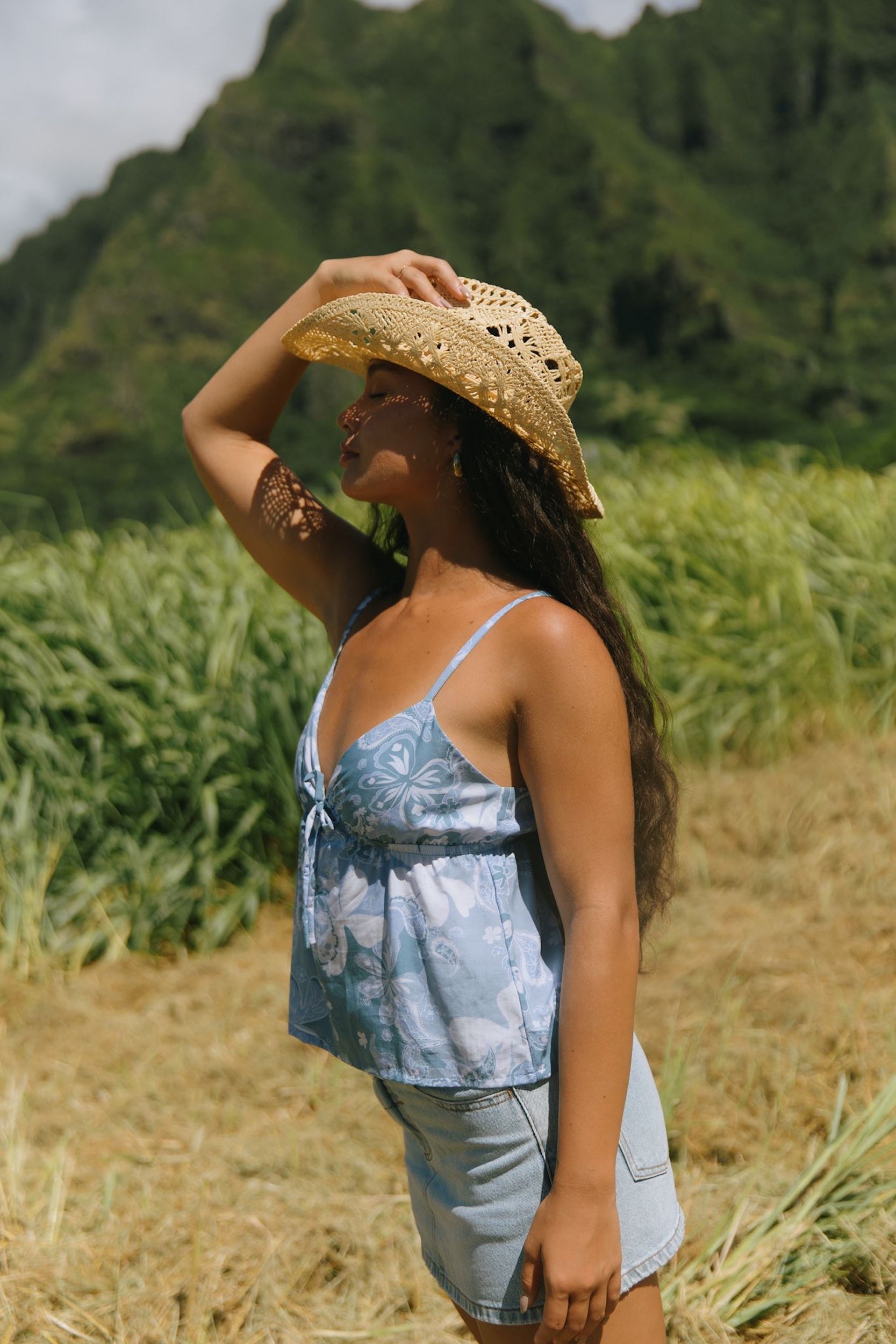 woman with brown hair wearing blue paisley printed spaghetti strap blouse with bow detail