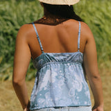 woman with brown hair wearing blue paisley printed spaghetti strap blouse with bow detail
