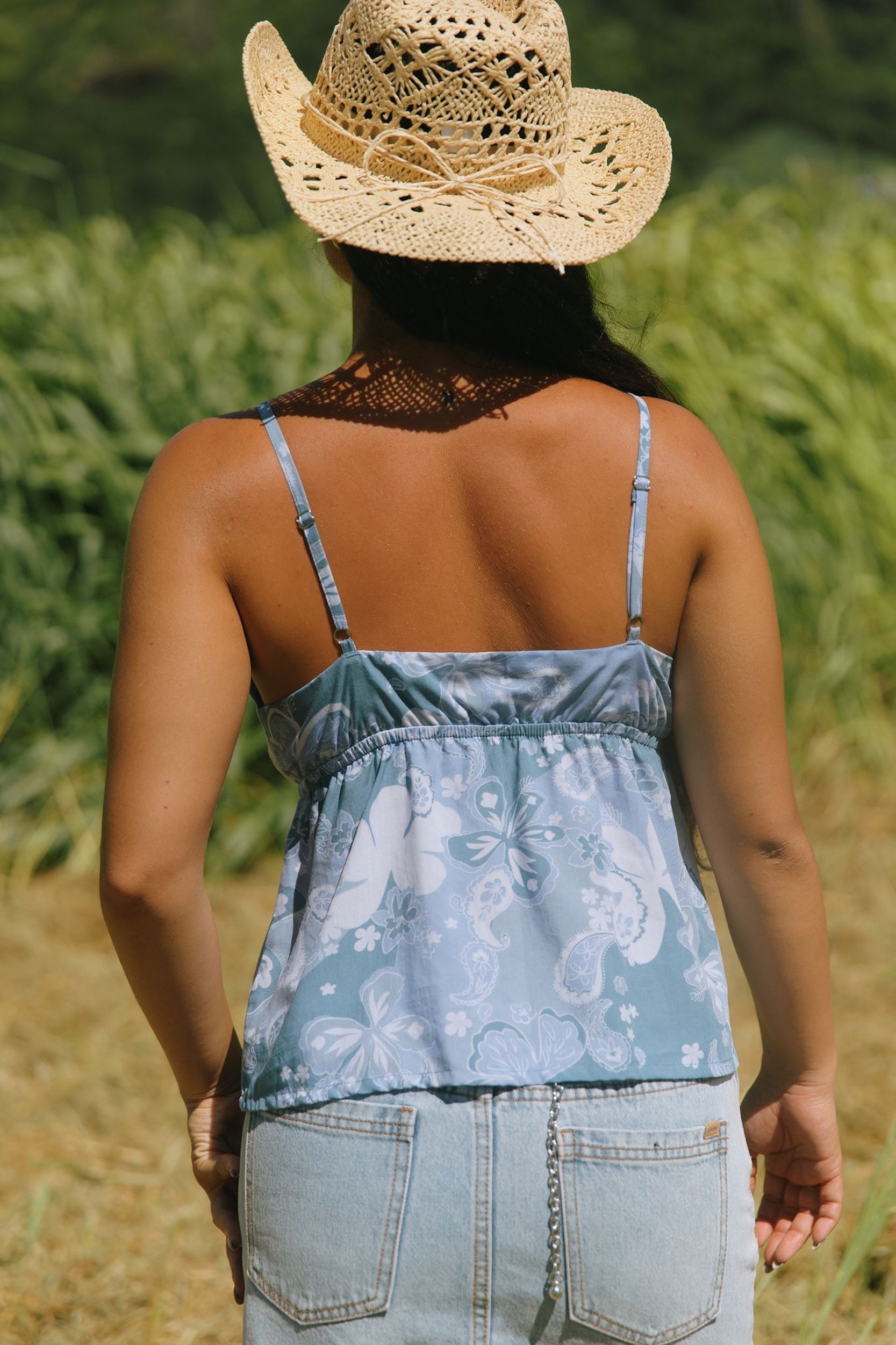 woman with brown hair wearing blue paisley printed spaghetti strap blouse with bow detail
