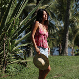 woman with brown hair wearing a pink spaghetti strap top with bow detail with shell and pua print