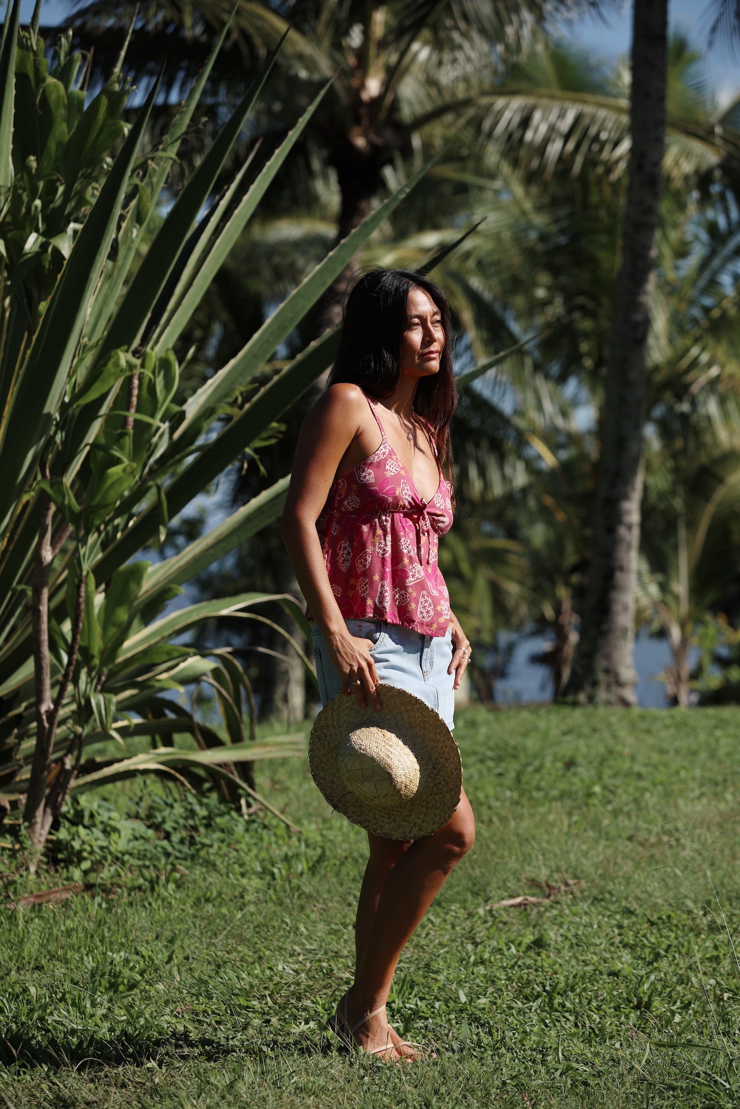 woman with brown hair wearing a pink spaghetti strap top with bow detail with shell and pua print