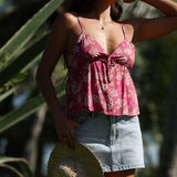 woman with brown hair wearing a pink spaghetti strap top with bow detail with shell and pua print