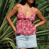 woman with brown hair wearing a pink spaghetti strap top with bow detail with shell and pua print