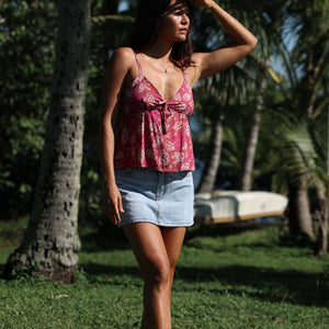 woman with brown hair wearing a pink spaghetti strap top with bow detail with shell and pua print