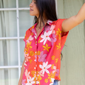 women with brown hair wearing a pink short sleeve button up top with retro flower pattern