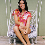 women with brown hair wearing a pink short sleeve button up top with retro flower pattern