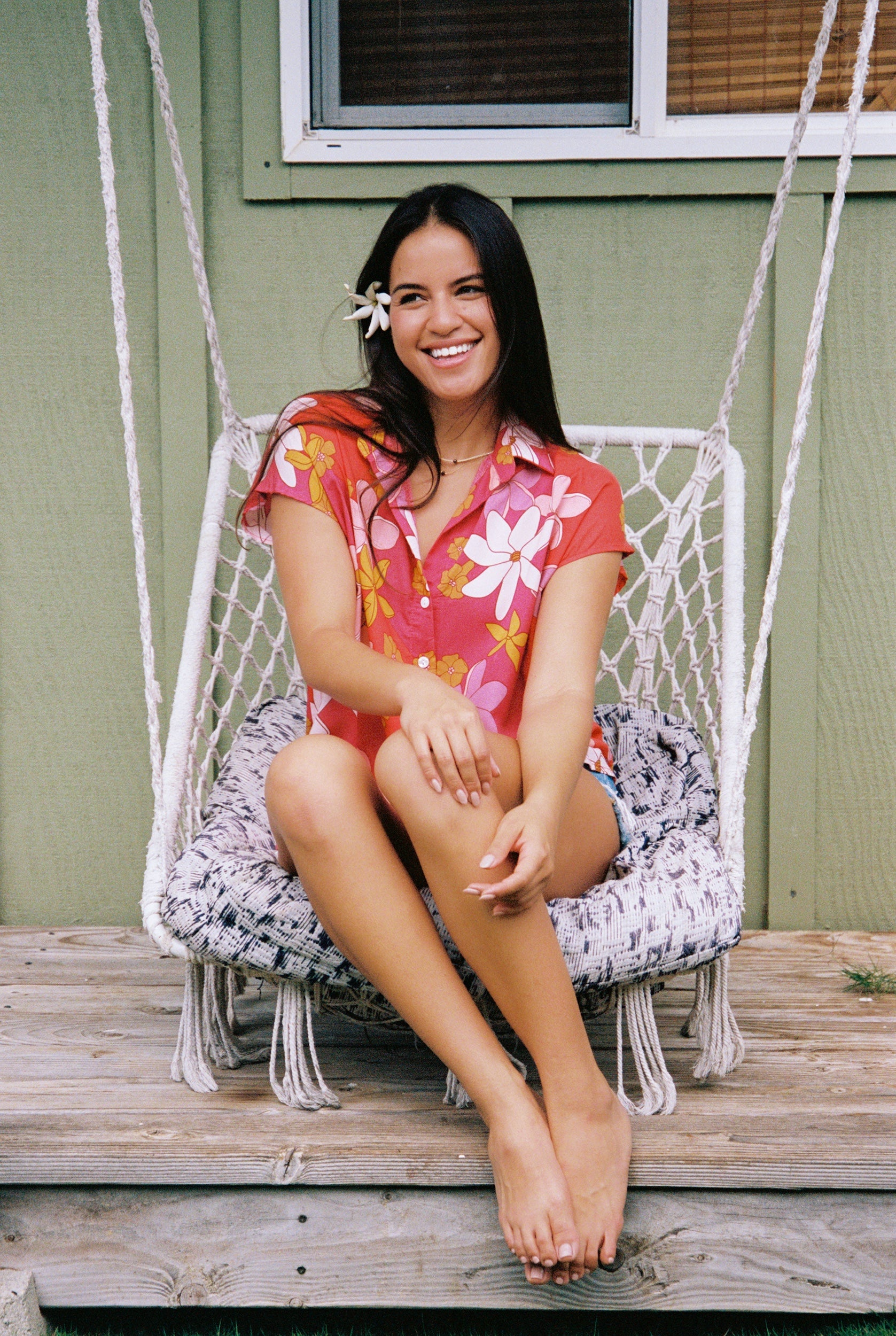 women with brown hair wearing a pink short sleeve button up top with retro flower pattern