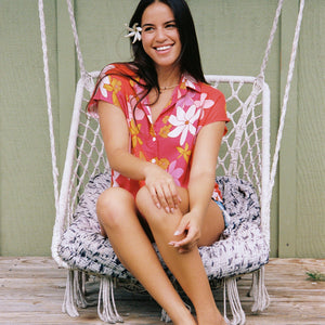 women with brown hair wearing a pink short sleeve button up top with retro flower pattern