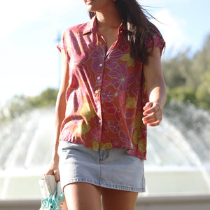 woman wearing terracotta colored button up top with large purple and yellow flower pattern