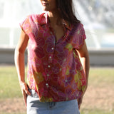 woman wearing terracotta colored button up top with large purple and yellow flower pattern