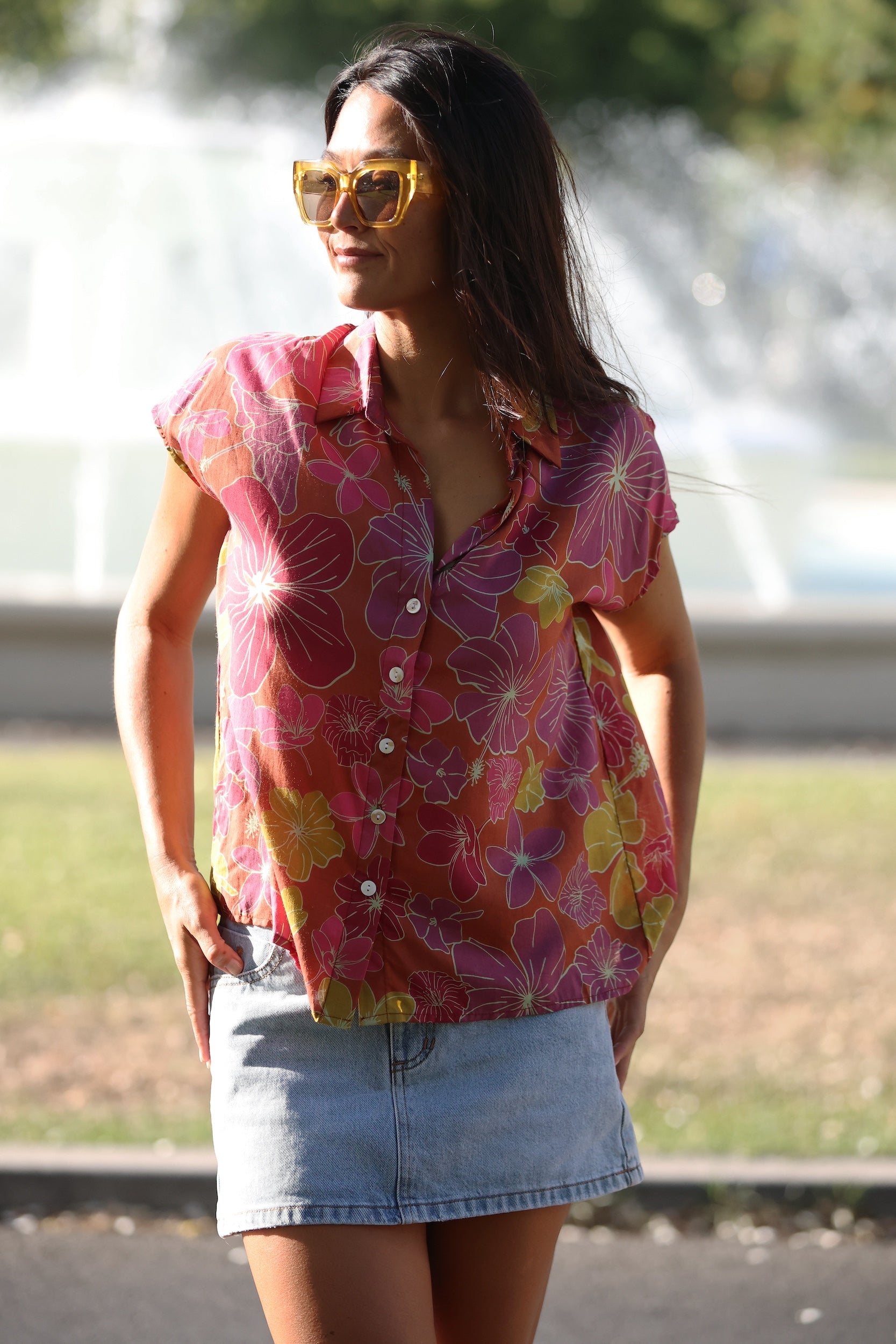 woman wearing terracotta colored button up top with large purple and yellow flower pattern