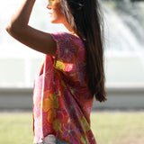 woman wearing terracotta colored button up top with large purple and yellow flower pattern