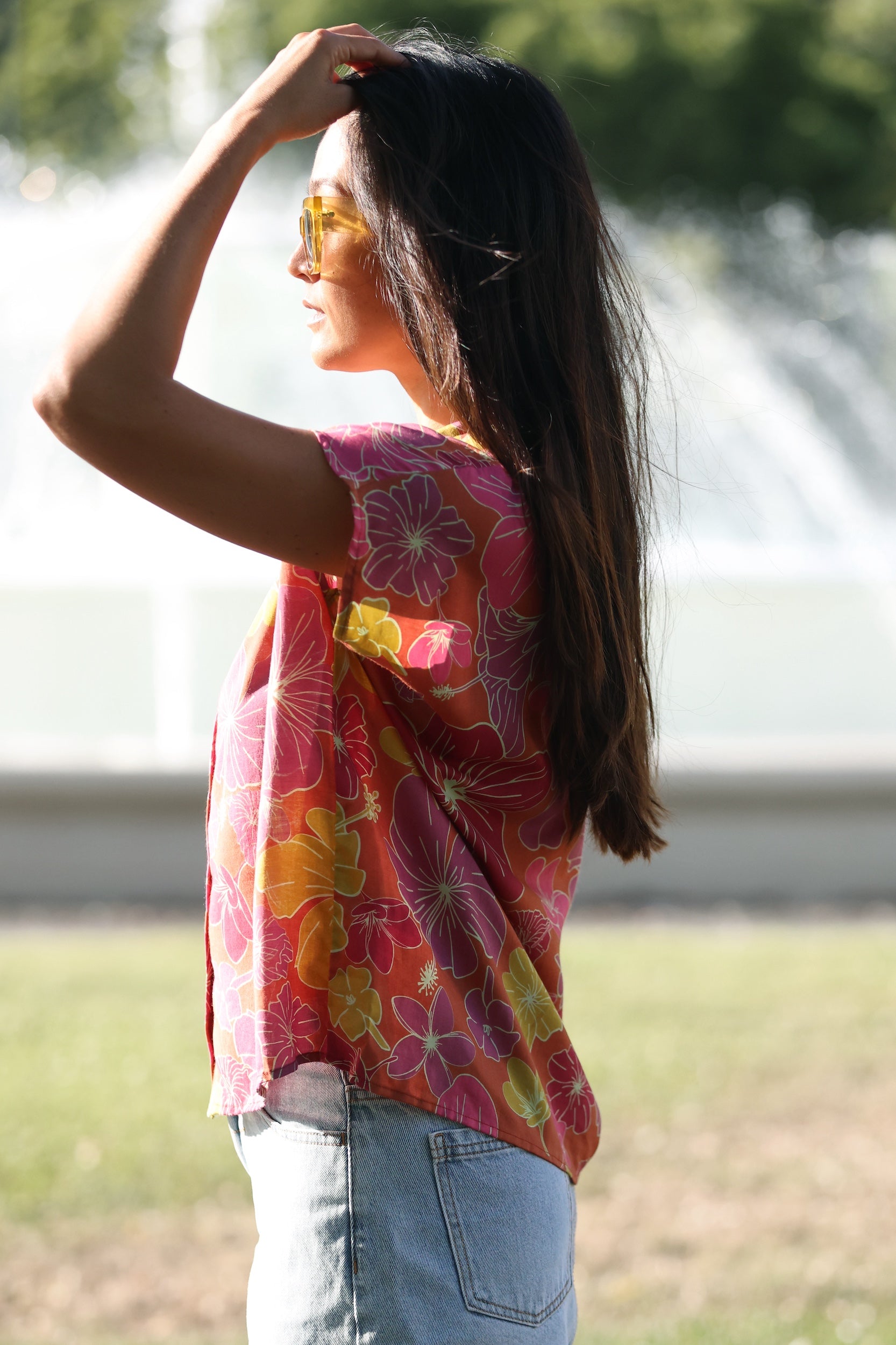 woman wearing terracotta colored button up top with large purple and yellow flower pattern