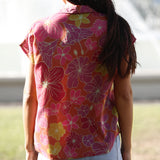 woman wearing terracotta colored button up top with large purple and yellow flower pattern