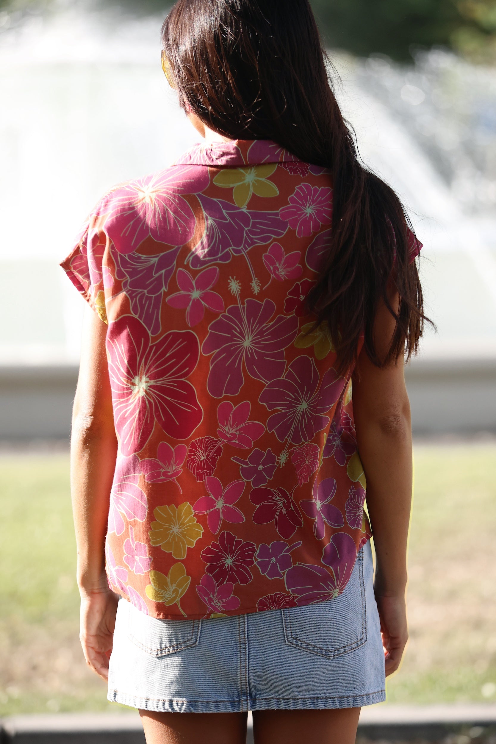 woman wearing terracotta colored button up top with large purple and yellow flower pattern