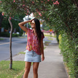 woman wearing terracotta colored button up top with large purple and yellow flower pattern 