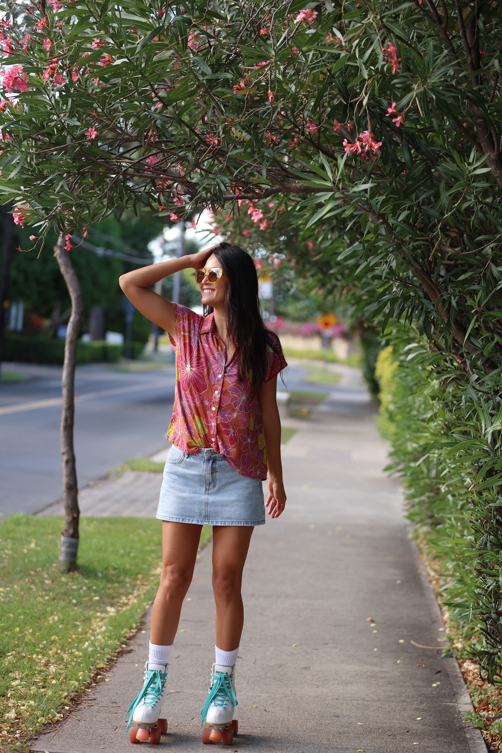 woman wearing terracotta colored button up top with large purple and yellow flower pattern 