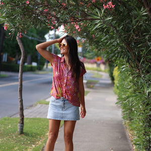 woman wearing terracotta colored button up top with large purple and yellow flower pattern 