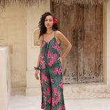 woman with brown hair wearing a dark green spaghetti strap jumpsuit with fern and ginger print