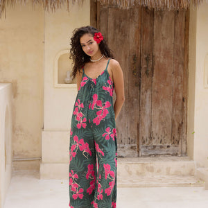 woman with brown hair wearing a dark green spaghetti strap jumpsuit with fern and ginger print