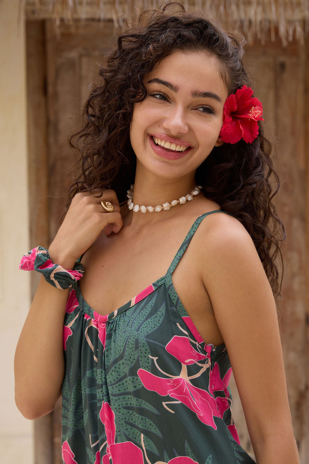 woman with brown hair wearing a dark green spaghetti strap jumpsuit with fern and ginger print