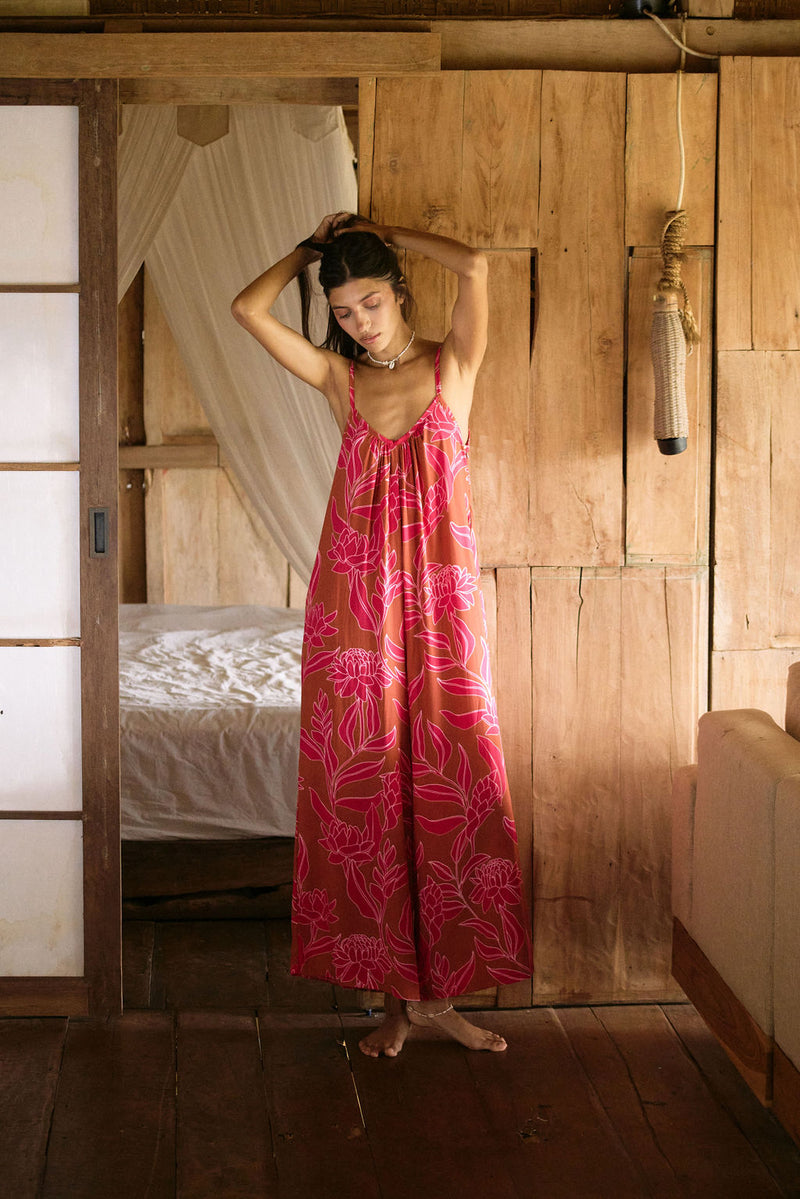 A woman with dark hair wears a YIREH v-neck, wide legged jumpsuit. It is the Laney Jumpsuit in the Garden 'Awapuhi print.