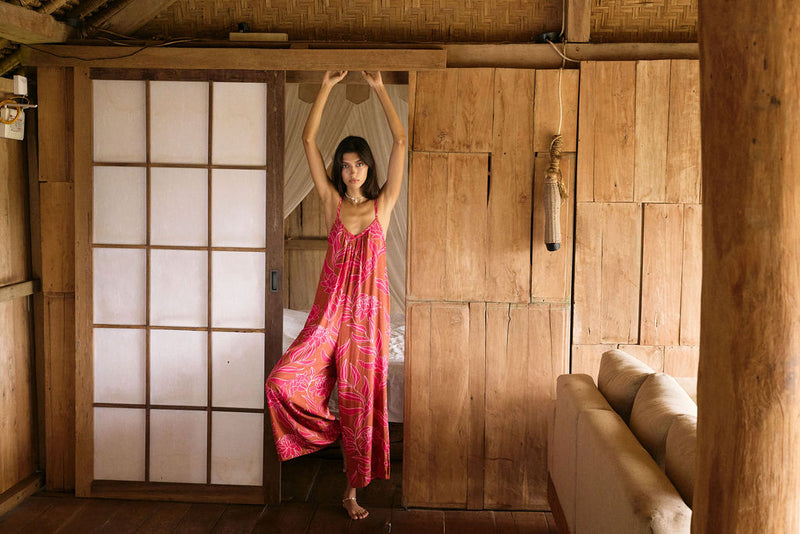 A woman with dark hair wears a YIREH v-neck, wide legged jumpsuit. It is the Laney Jumpsuit in the Garden 'Awapuhi print. 