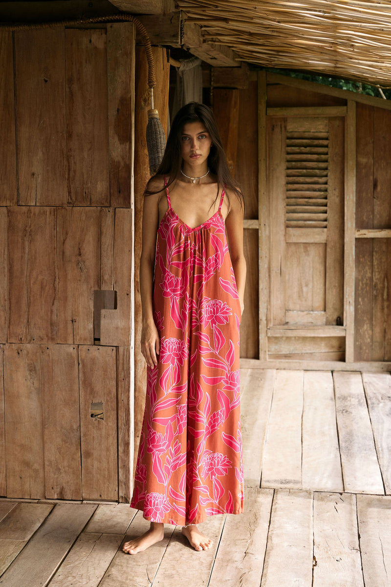 A woman with dark hair wears a YIREH v-neck, wide legged jumpsuit. It is the Laney Jumpsuit in the Garden 'Awapuhi print. 