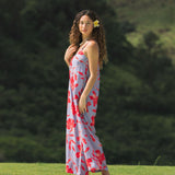 woman with brown hair wearing a jumpsuit with periwinkle background and bright red hibiscus print.