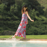woman with brown hair wearing a jumpsuit with periwinkle background and bright red hibiscus print.