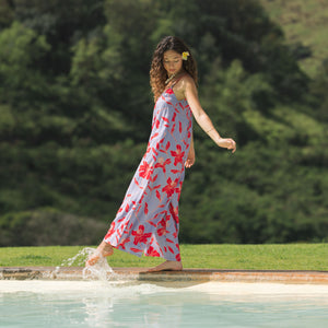 woman with brown hair wearing a jumpsuit with periwinkle background and bright red hibiscus print.
