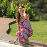 woman with brown hair wearing a jumpsuit with periwinkle background and bright red hibiscus print.