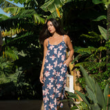 woman with black hair wearing a jumpsuit in a navy color with pink hibiscus blossoms 