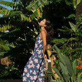 woman with black hair wearing a jumpsuit in a navy color with pink hibiscus blossoms 