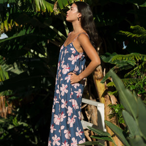 woman with black hair wearing a jumpsuit in a navy color with pink hibiscus blossoms 