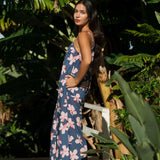 woman with black hair wearing a jumpsuit in a navy color with pink hibiscus blossoms 