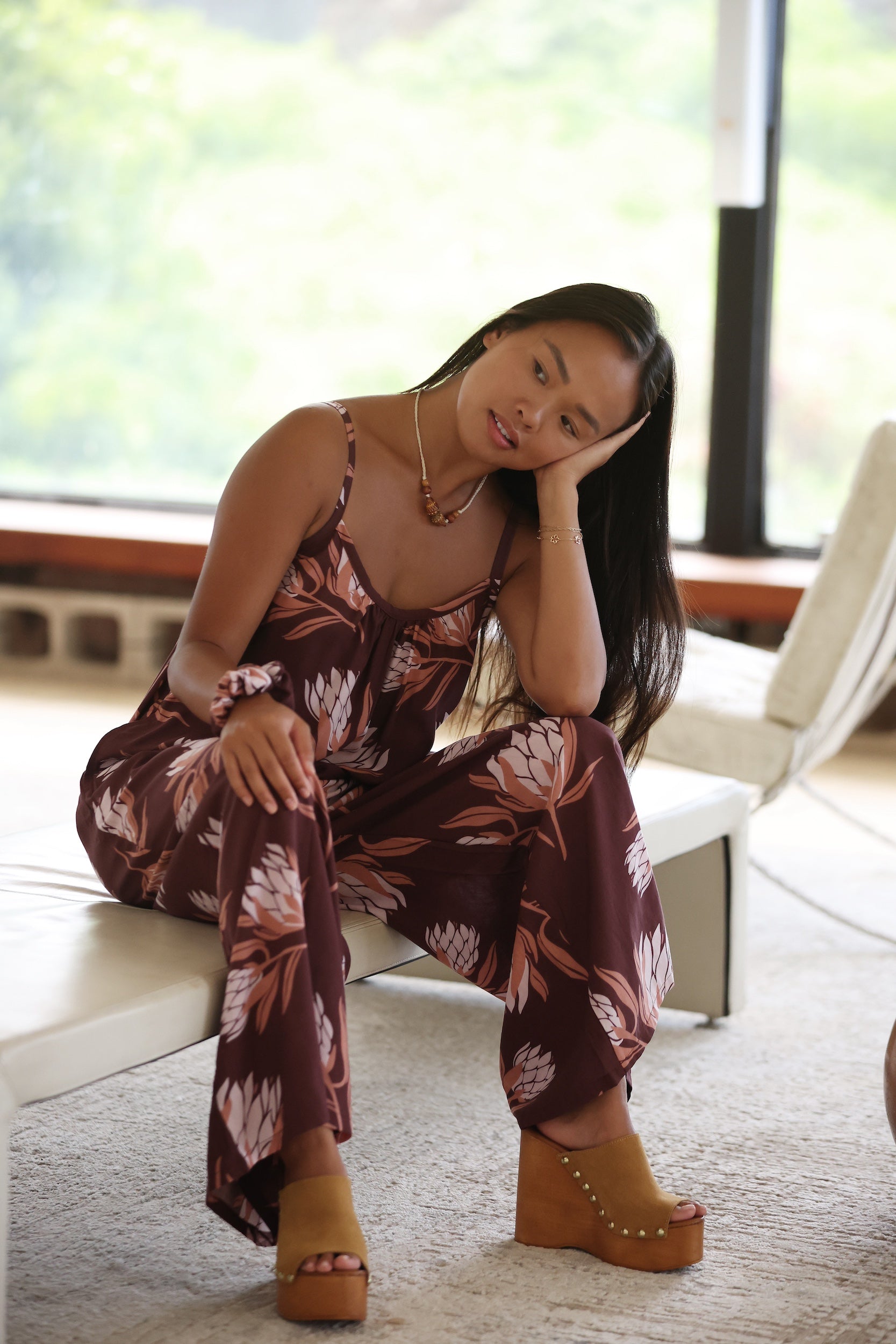 woman wearing simple brown spaghetti strap jumpsuit with protea print