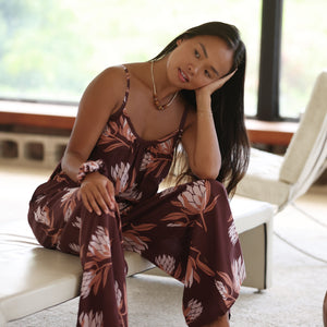 woman wearing simple brown spaghetti strap jumpsuit with protea print