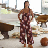 woman wearing simple brown spaghetti strap jumpsuit with protea print