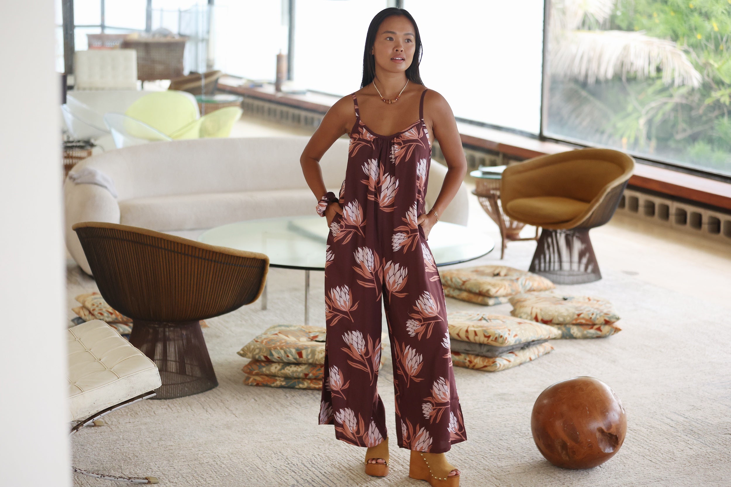 woman wearing simple brown spaghetti strap jumpsuit with protea print